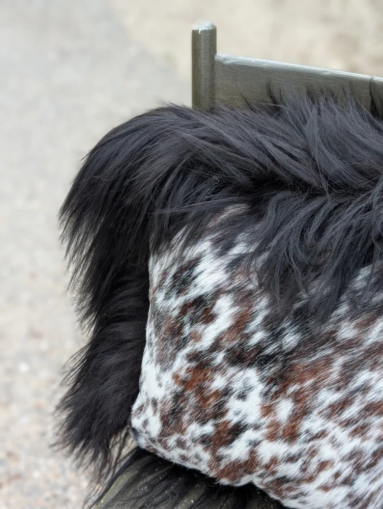 Speckled cowhide pillow with natural cowhide spots and fluffy black long wool faux fur trim perfect for cozy decor