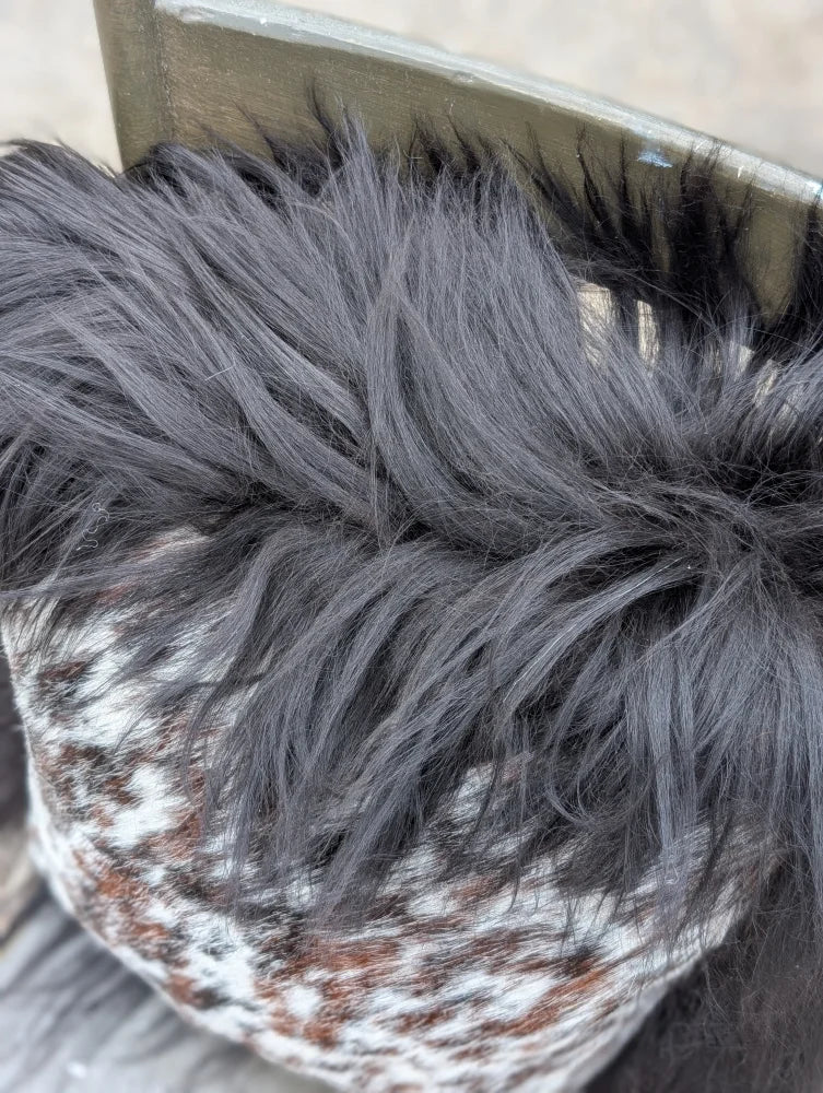 A cozy knit pillow with natural cowhide pattern and dark gray long wool faux fur trim perfect for sewing machines use