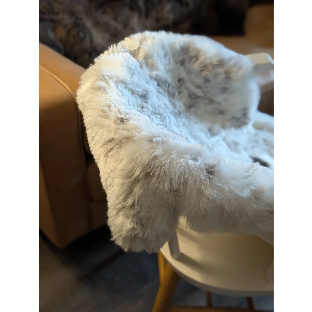 A plush white icelandic sheepskin throw with short wool texture and subtle gray speckles perfect for cozy decor