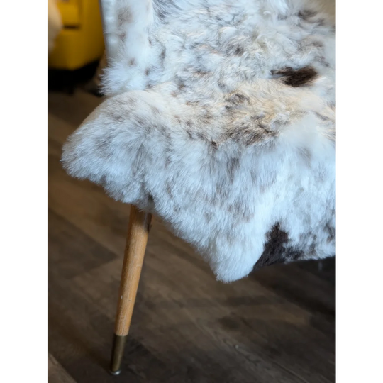 A plush icelandic sheepskin throw in soft white gray and brown tones with short wool draped over a chair leg