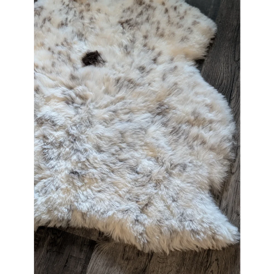 A plush cream-colored icelandic sheepskin rug with natural black and gray speckles and short wool texture