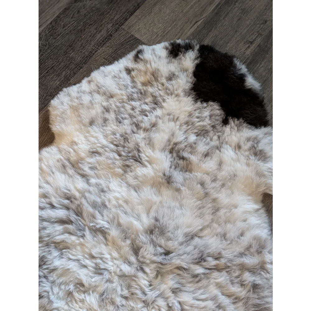 A plush icelandic sheepskin rug with soft white and black short wool spots perfect for cozy decor