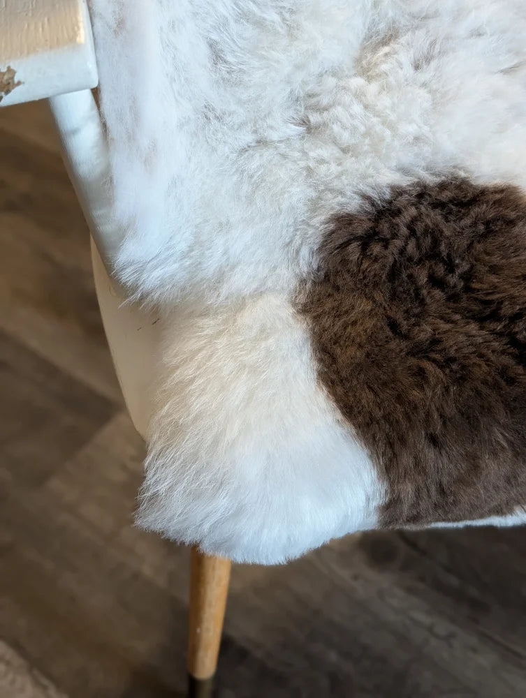 A cozy plush medium spotted icelandic sheepskin throw with soft white and rich brown short wool patchwork design