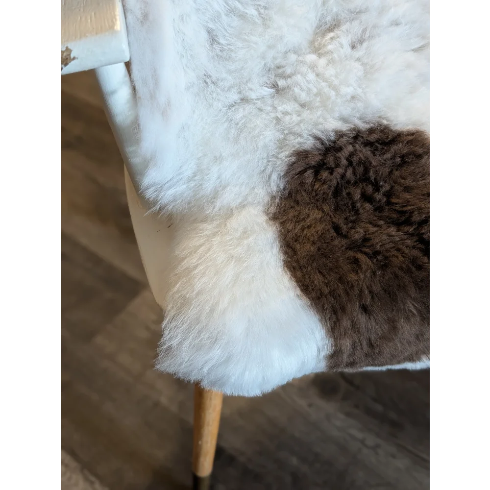 A cozy plush medium spotted icelandic sheepskin throw with soft white and rich brown short wool patchwork design