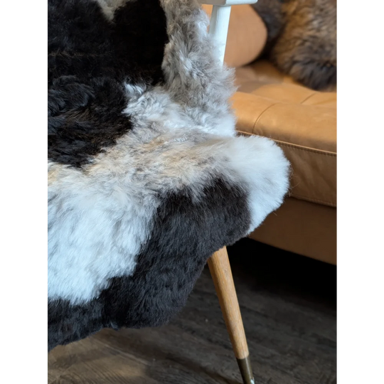 A plush icelandic sheepskin rug with patchwork natural black and white short wool fur measuring 42 by 29.5 inches