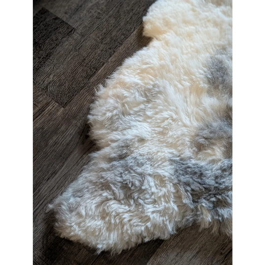 Cream and gray medium spotted icelandic sheepskin rug with soft fluffy short wool texture 40.5 by 29.5 inches