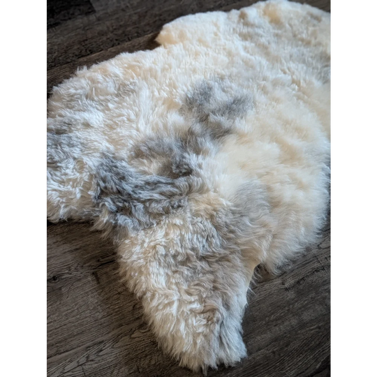 A plush icelandic sheepskin rug with short wool in cream and gray spots perfect for cozy home decor