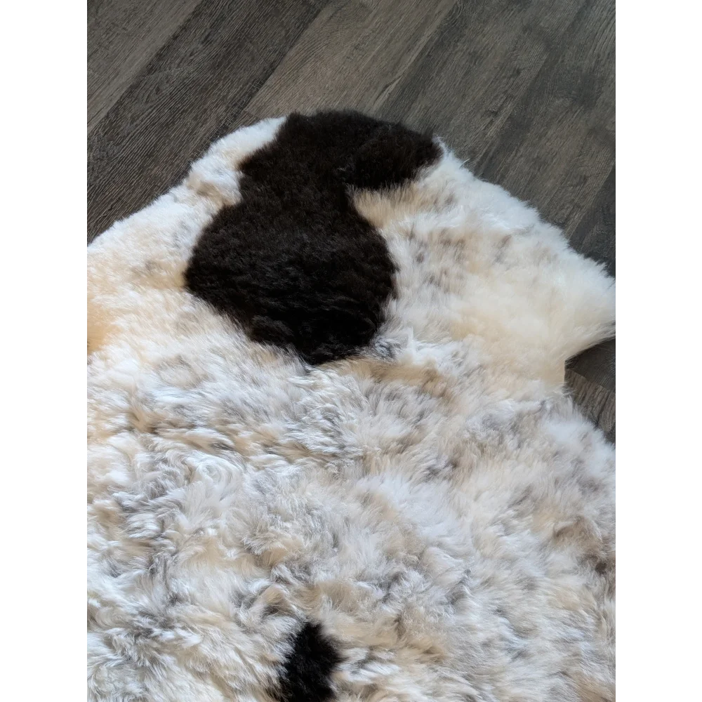 A cream-colored icelandic sheepskin rug with short wool and a black spot resembling a dog’s ear medium size
