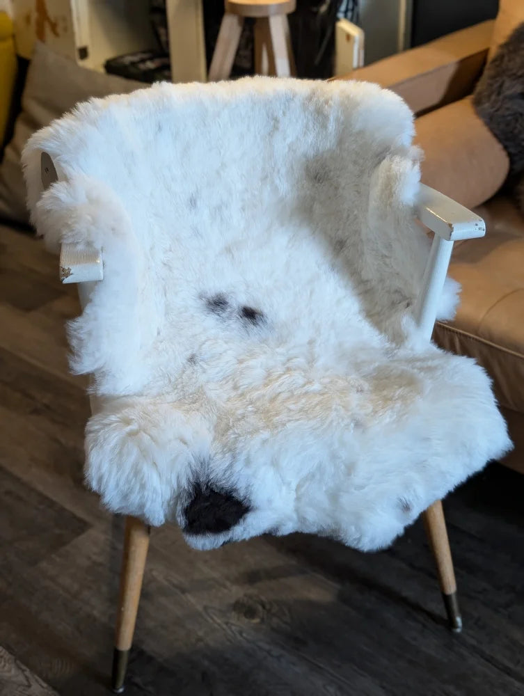 White fur-covered chair with wooden legs featuring a cozy icelandic sheepskin with short wool texture