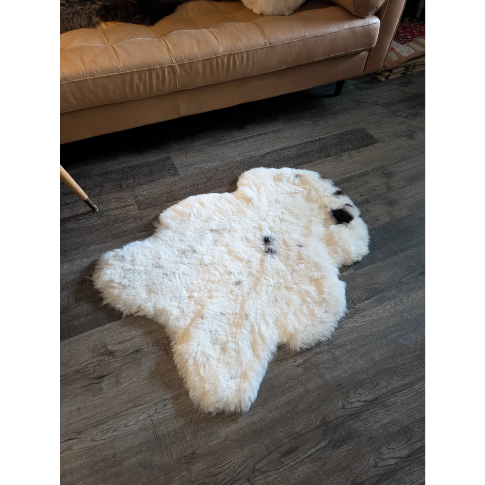 White icelandic sheepskin rug with natural black spots made of soft short wool measuring 41 by 32 inches