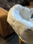 A plush white icelandic sheepskin throw with short wool draped over the edge of a light-colored table