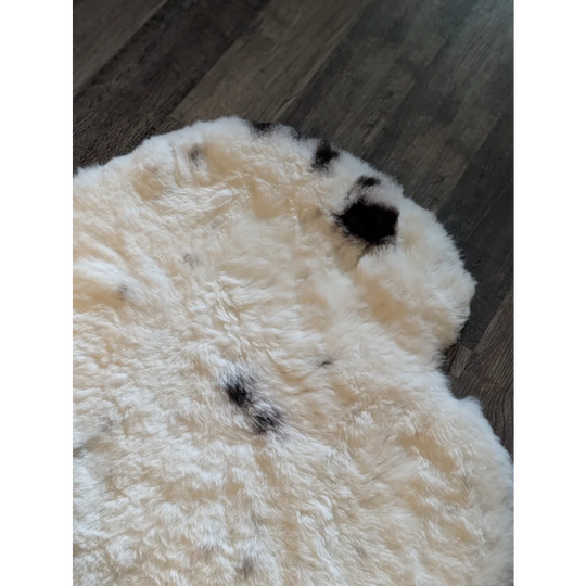 Cream-colored icelandic sheepskin rug with black speckles made of medium short wool 41 by 32 inches