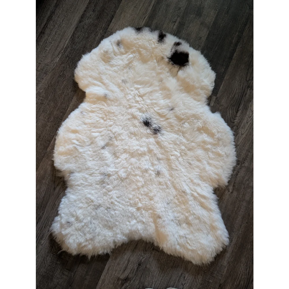 A medium cream icelandic sheepskin rug with black spots made of short wool perfect for cozy decor