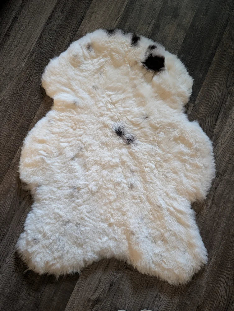 A medium cream icelandic sheepskin rug with black spots made of short wool perfect for cozy decor