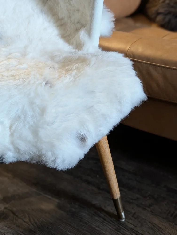 White fluffy spotted icelandic sheepskin chair cover with short wool and subtle beige patches soft natural texture