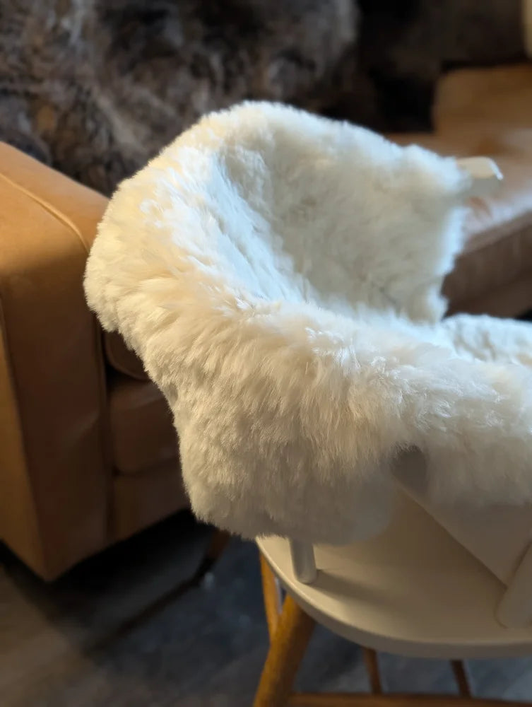 White fluffy icelandic sheepskin short wool throw draped over white high chair for cozy seating