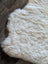 Cream-colored plush icelandic sheepskin rug with soft short wool and natural irregular edges 40.5 x 32 inches