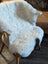 White icelandic sheepskin chair cover with soft short wool texture and subtle black patch near the seat