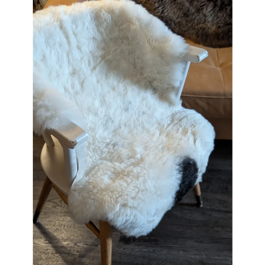 White icelandic sheepskin chair cover with soft short wool texture and subtle black patch near the seat