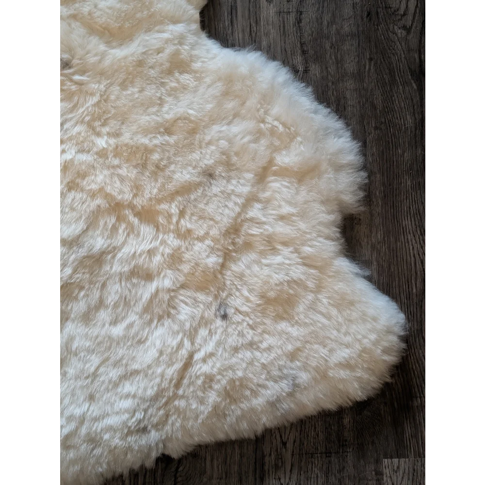 Cream-colored plush medium spotted icelandic sheepskin rug with soft short wool and natural irregular edges