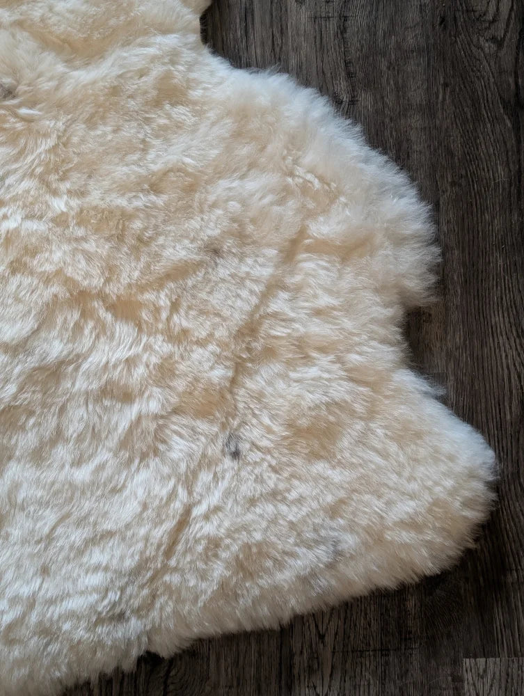 Cream-colored plush medium spotted icelandic sheepskin rug with soft short wool and natural irregular edges