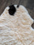 Cream-colored icelandic sheepskin rug with a single black patch featuring short wool texture for cozy use