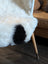 White icelandic sheepskin throw with a black patch made of short wool draped over a modern chair leg