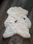 Cream-colored fluffy medium icelandic sheepskin rug with natural black markings and short wool texture spot2 heart