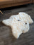 A plush off-white medium icelandic sheepskin rug with short wool texture and two small black patches on the surface