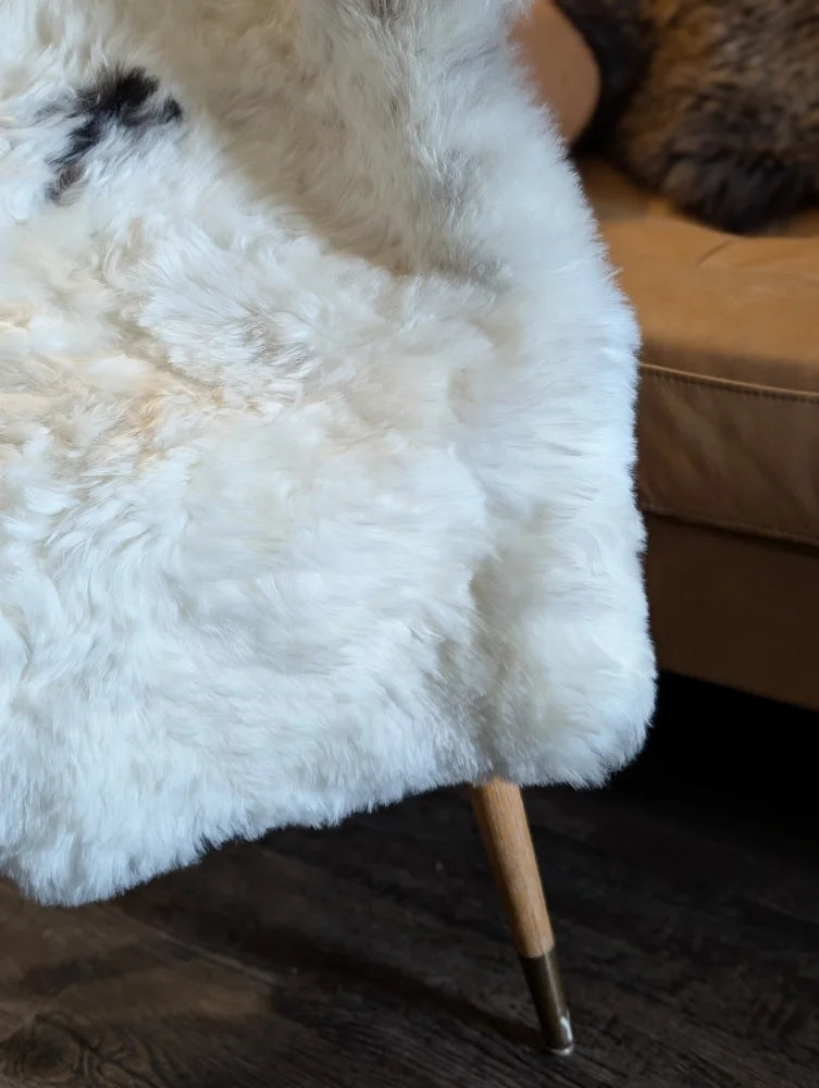 White fluffy medium spotted icelandic sheepskin throw with short wool draped over a wooden-legged chair