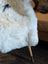 White fluffy medium spotted icelandic sheepskin throw with short wool draped over a wooden-legged chair