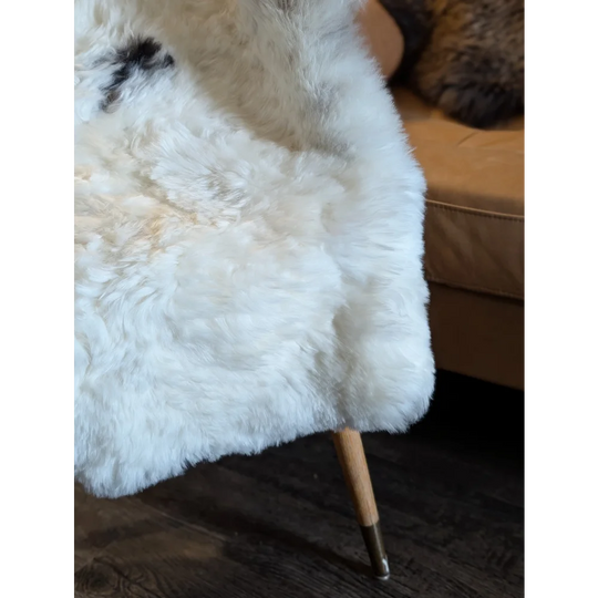 White fluffy medium spotted icelandic sheepskin throw with short wool draped over a wooden-legged chair