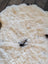 Cream-colored fluffy icelandic sheepskin rug with natural black patches short wool medium size 42 by 32 inches