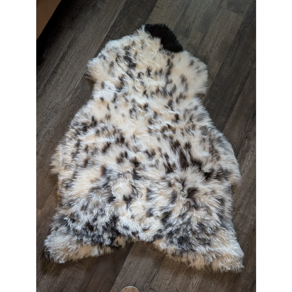 A plush cream and black speckled icelandic sheepskin rug with soft short wool texture in large 48 x 33 size