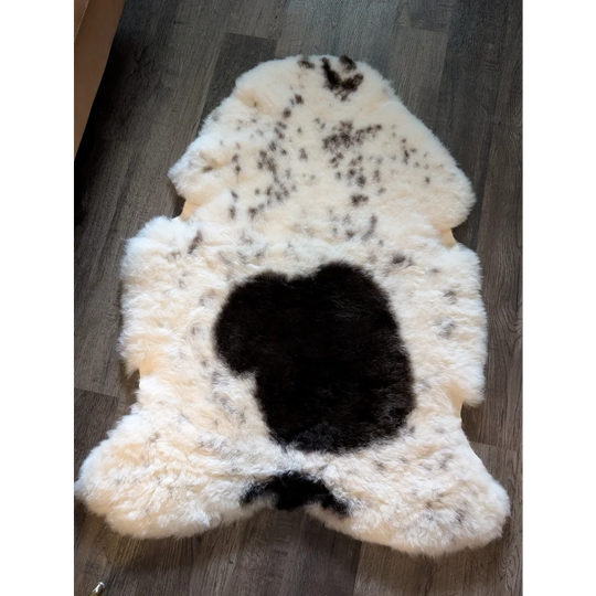 Cream-colored large icelandic sheepskin rug with black cow print design made of short wool spot22 48 x 34 inches