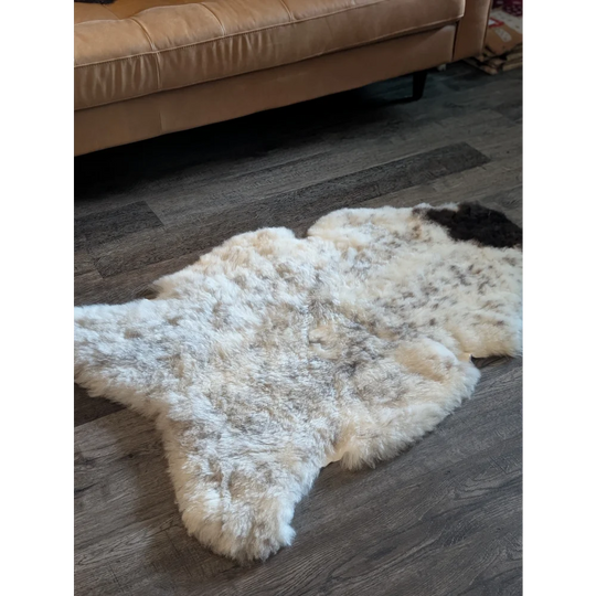A fluffy large icelandic sheepskin rug with white and dark gray short wool in an irregular spotted shape