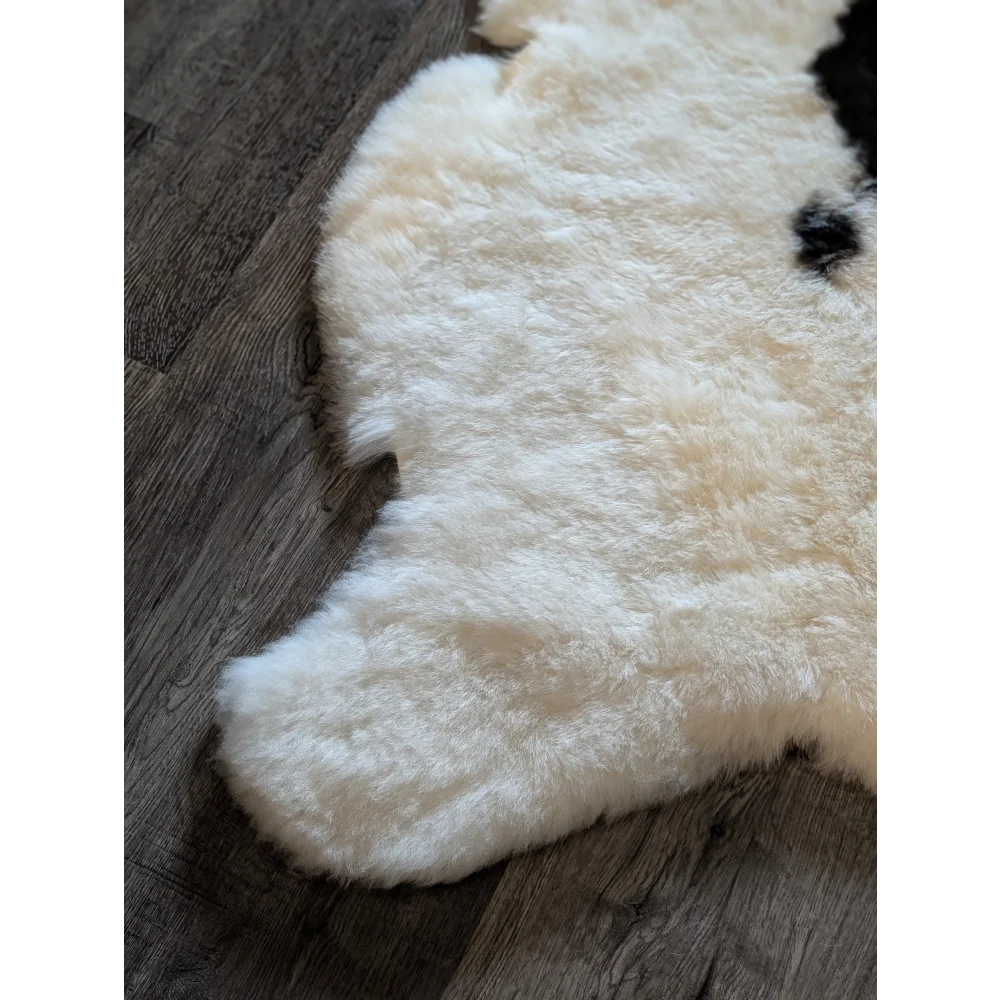 Cream-colored icelandic sheepskin rug with natural black patches and soft short wool texture 49 x 32 inches
