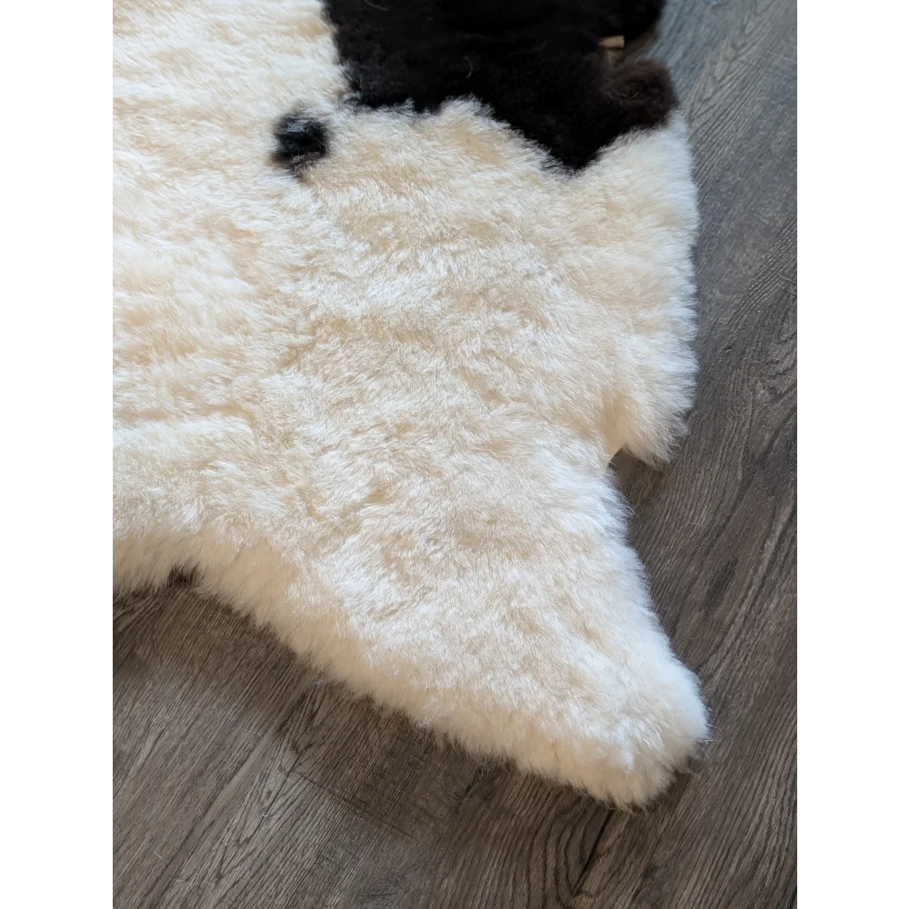 Cream-colored fluffy icelandic sheepskin rug with short wool and black patch spotted 49 x 32 inches