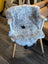 A plush gray and white icelandic sheepskin chair cover with soft short wool and fluffy texture for cozy seating