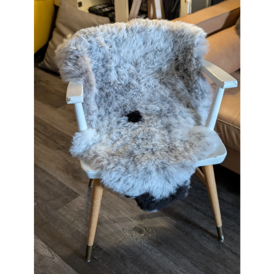 A plush gray and white icelandic sheepskin chair cover with soft short wool and fluffy texture for cozy seating