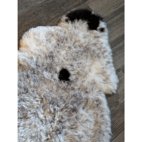 A plush icelandic sheepskin rug with short wool in cream and gray hues featuring black patches spot3 medium size