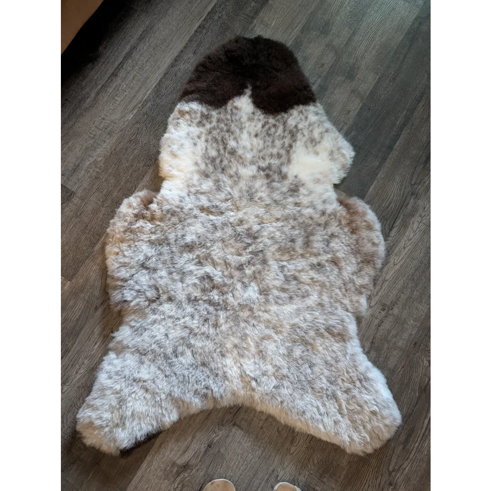 A large spotted icelandic sheepskin rug with short wool in white and brown featuring a darker patch at the top