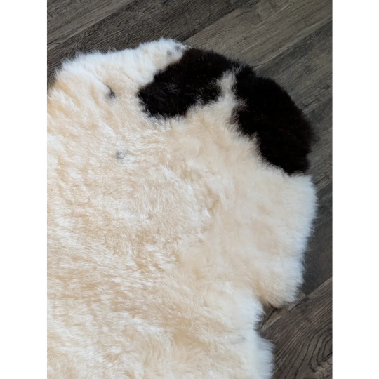 Cream-colored icelandic sheepskin rug with a black fur patch made of short wool ideal for cozy decor