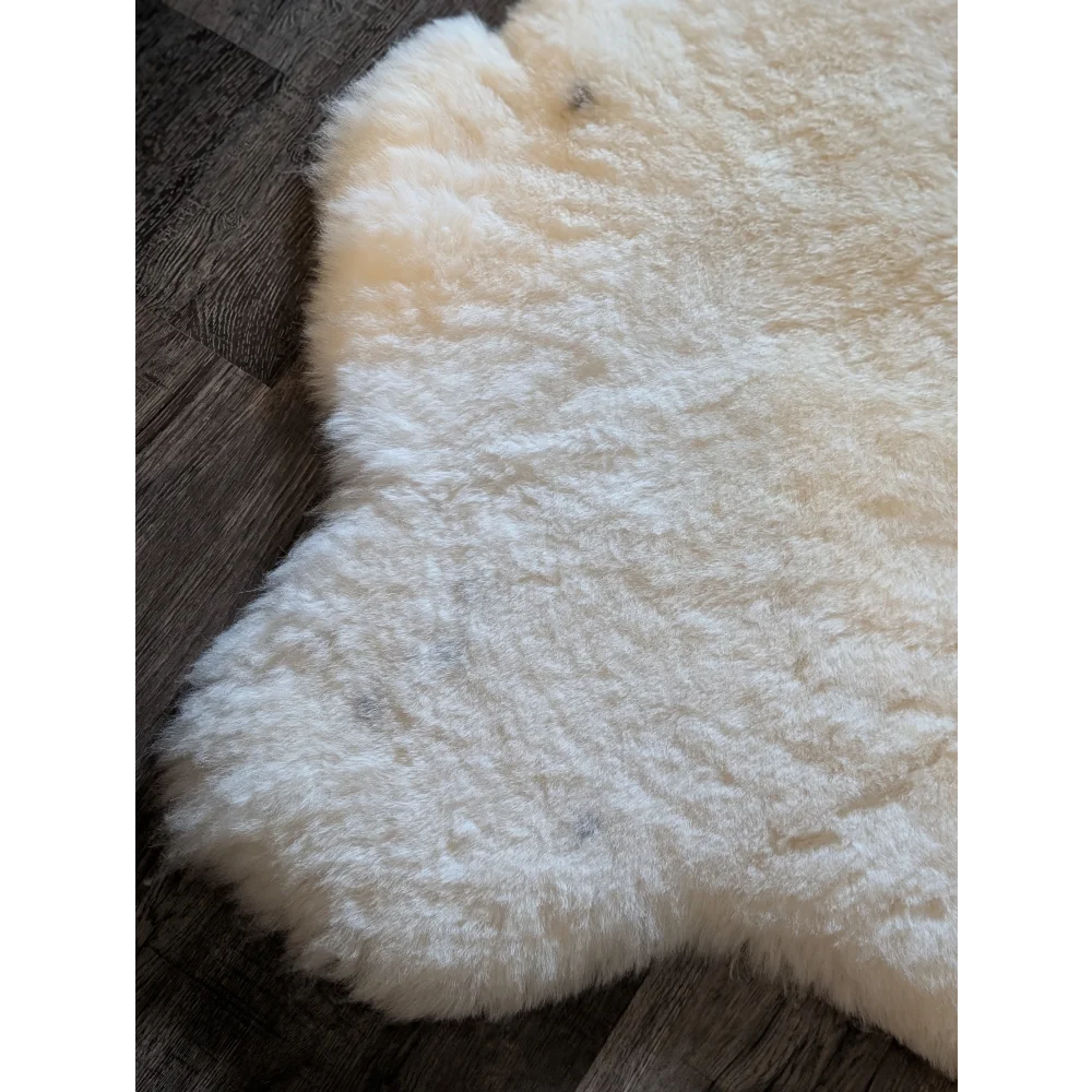 Cream-colored plush icelandic sheepskin rug with natural edges made from short wool for cozy decor