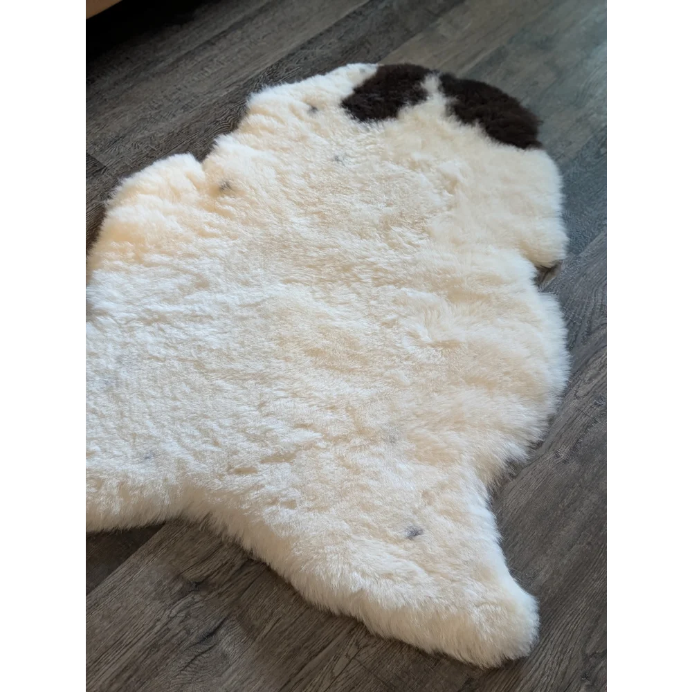 Cream-colored icelandic sheepskin rug with dark brown patches featuring short wool for cozy home decor