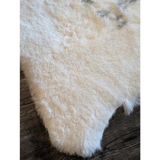 A plush off-white icelandic sheepskin rug with short wool and natural irregular edges measuring 47.7 by 31 inches