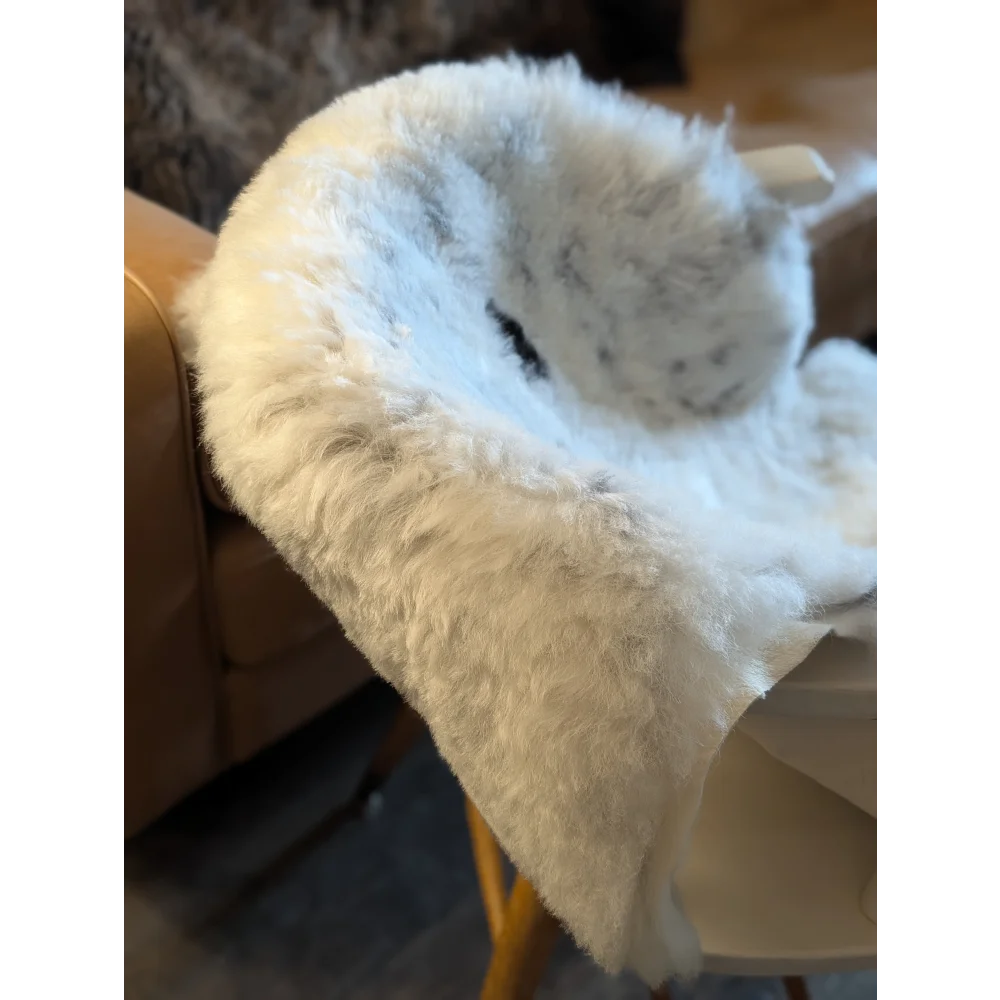 A plush white and gray icelandic sheepskin throw with short wool draped over the back of a chair