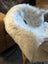 A plush white and gray icelandic sheepskin throw with short wool draped over the back of a chair