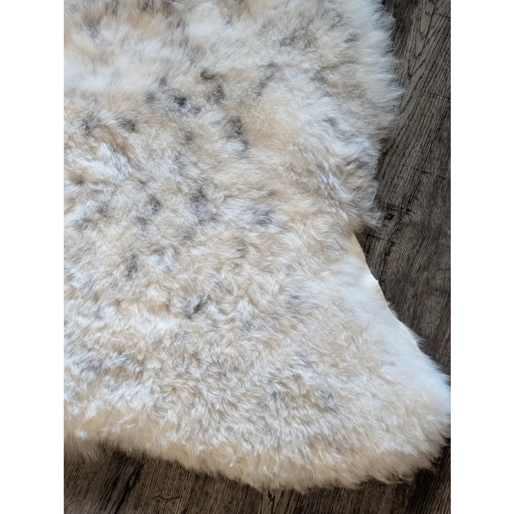 A plush cream-colored icelandic sheepskin rug with soft short wool and subtle gray speckles 45 by 31 inches