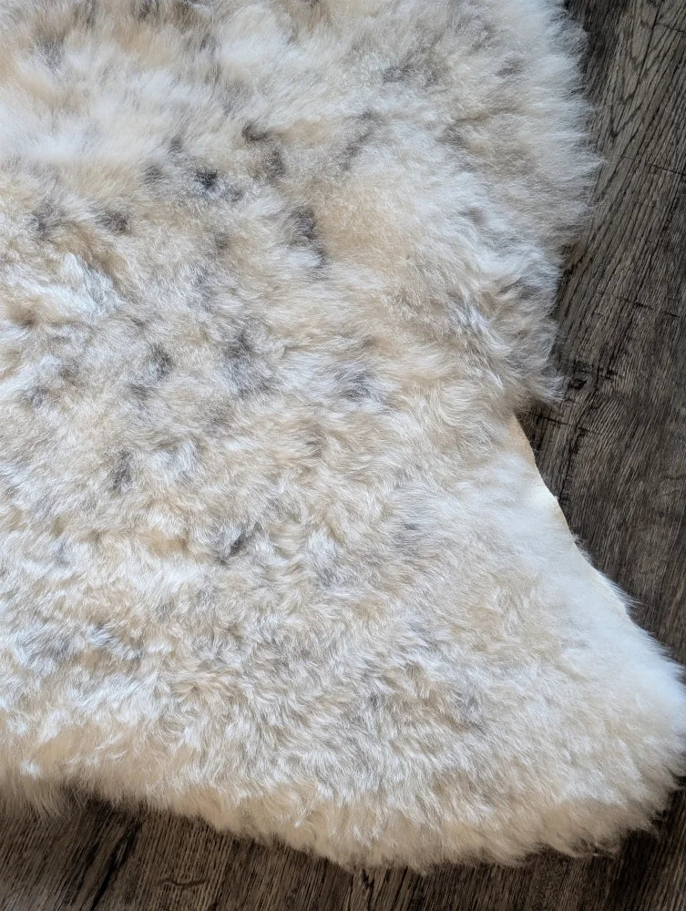 A plush cream-colored icelandic sheepskin rug with soft short wool and subtle gray speckles 45 by 31 inches